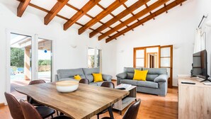 A spacious living area with a wooden dining table, grey sofas with yellow cushions, and a wooden cabinet. - Villa Flomertor 2  (Ciutadella de Menorca)