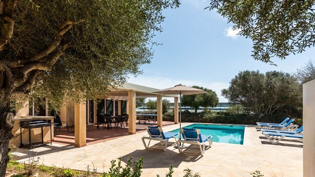 A poolside area with lounge chairs, a barbecue setup, and a pergola providing shade. - Villa Flomertor 2  (Ciutadella de Menorca)