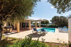A poolside area with lounge chairs, a barbecue setup, and a pergola providing shade. - Villa Flomertor 2  (Ciutadella de Menorca)