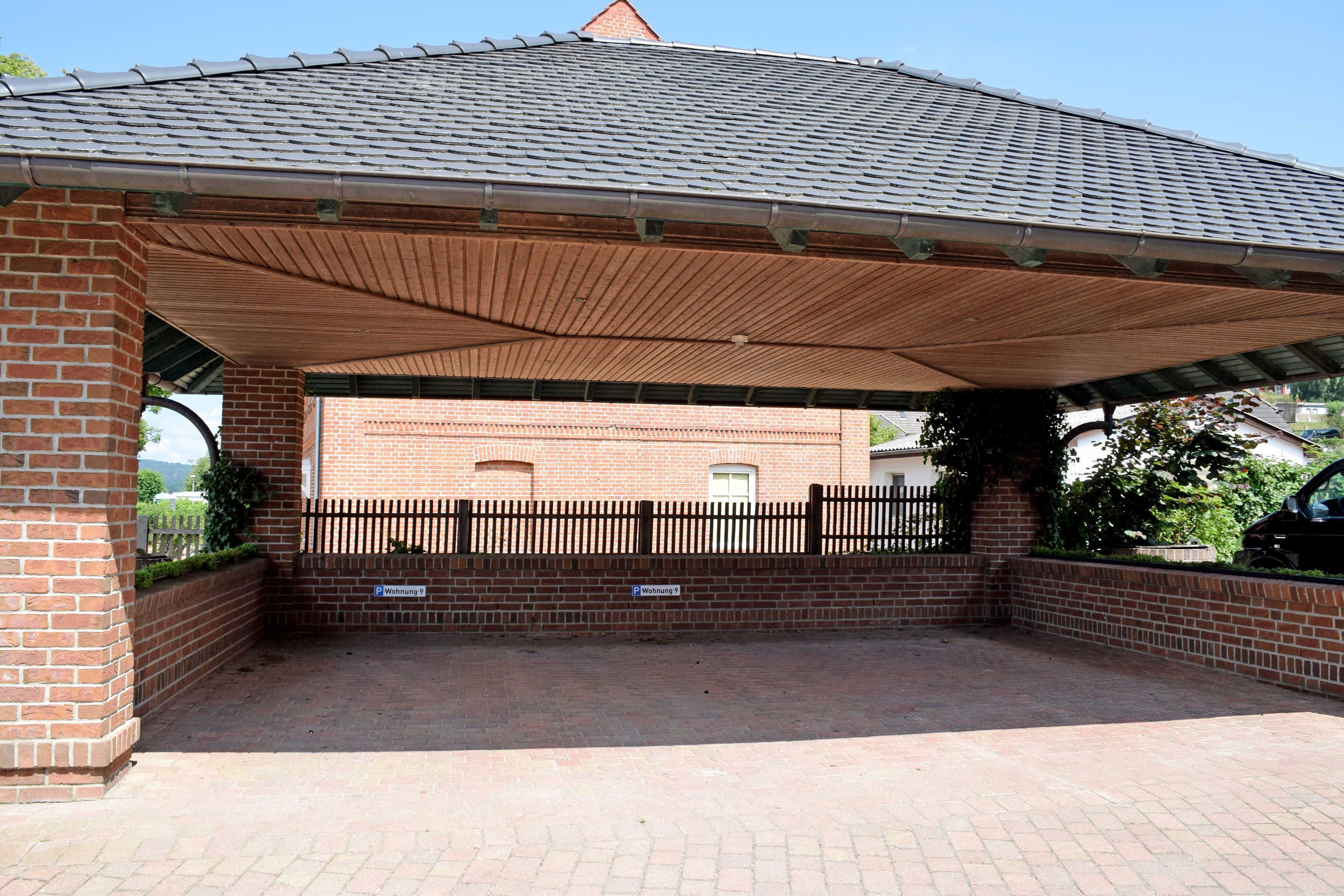 A covered outdoor area with a brick wall and a metal roof.