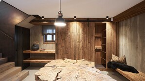 A modern interior with a large wooden table, built-in shelving, and a staircase. - Chalet Hirschbergblick (Rottach-Egern)