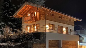 A two-story wooden house with a balcony, a stone wall, and a garage. - Chalet Hirschbergblick (Rottach-Egern)