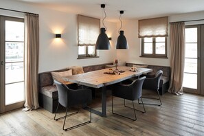 A dining area with a wooden table, black chairs, and pendant lights.