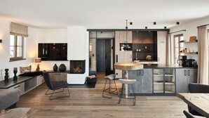A modern kitchen with a central island, bar stools, and a dining table. - Chalet Hirschbergblick (Rottach-Egern)