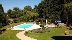Ein Garten mit Swimmingpool, Grill und überdachter Sitzgelegenheit.