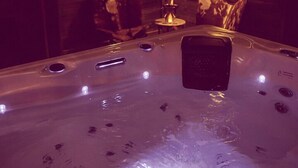 Ein Whirlpool in einem Holzraum mit geneigten Decken und Wandleuchten.