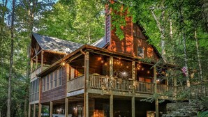 A wooden cabin with a balcony, surrounded by trees. - Nice & Knotty On The River | Ellijay, GA (Ellijay)