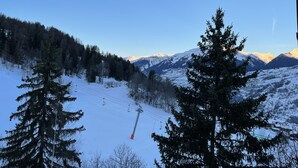 Un paysage de montagne enneigé avec un télésiège, des arbres et un ciel dégagé.