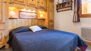 Une chambre à coucher avec un lit, une tête de lit en bois, des étagères fixées au mur et une fenêtre avec des rideaux.