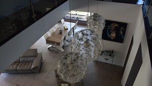 Un salon moderne comprenant un coin repas, un canapé, une table basse en verre et une grande œuvre d’art abstraite accrochée au mur.