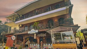A two-story building with a sign for "Lazy Fish Restaurant" and a sign for "Vaggi's Place". - Treebo Trip Lazy Holidays (Arpora)