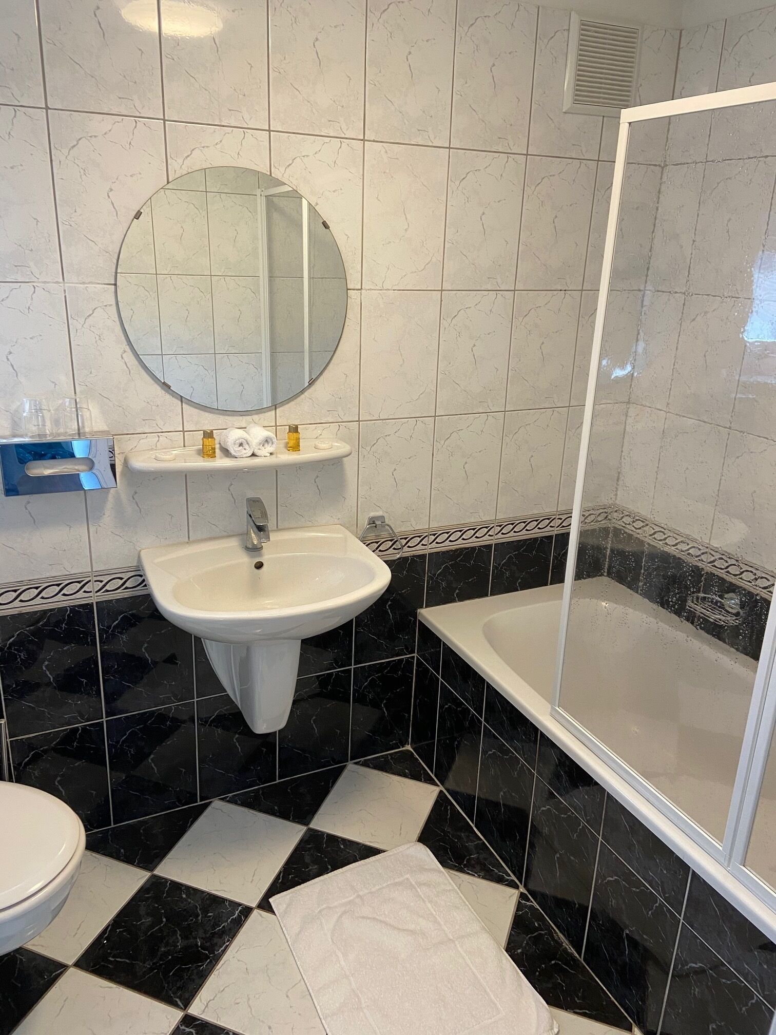 Een bad/douchecombinatie, een haardroger, handdoeken, zeep