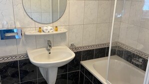 Een badkamer met wastafel, spiegel en bad.