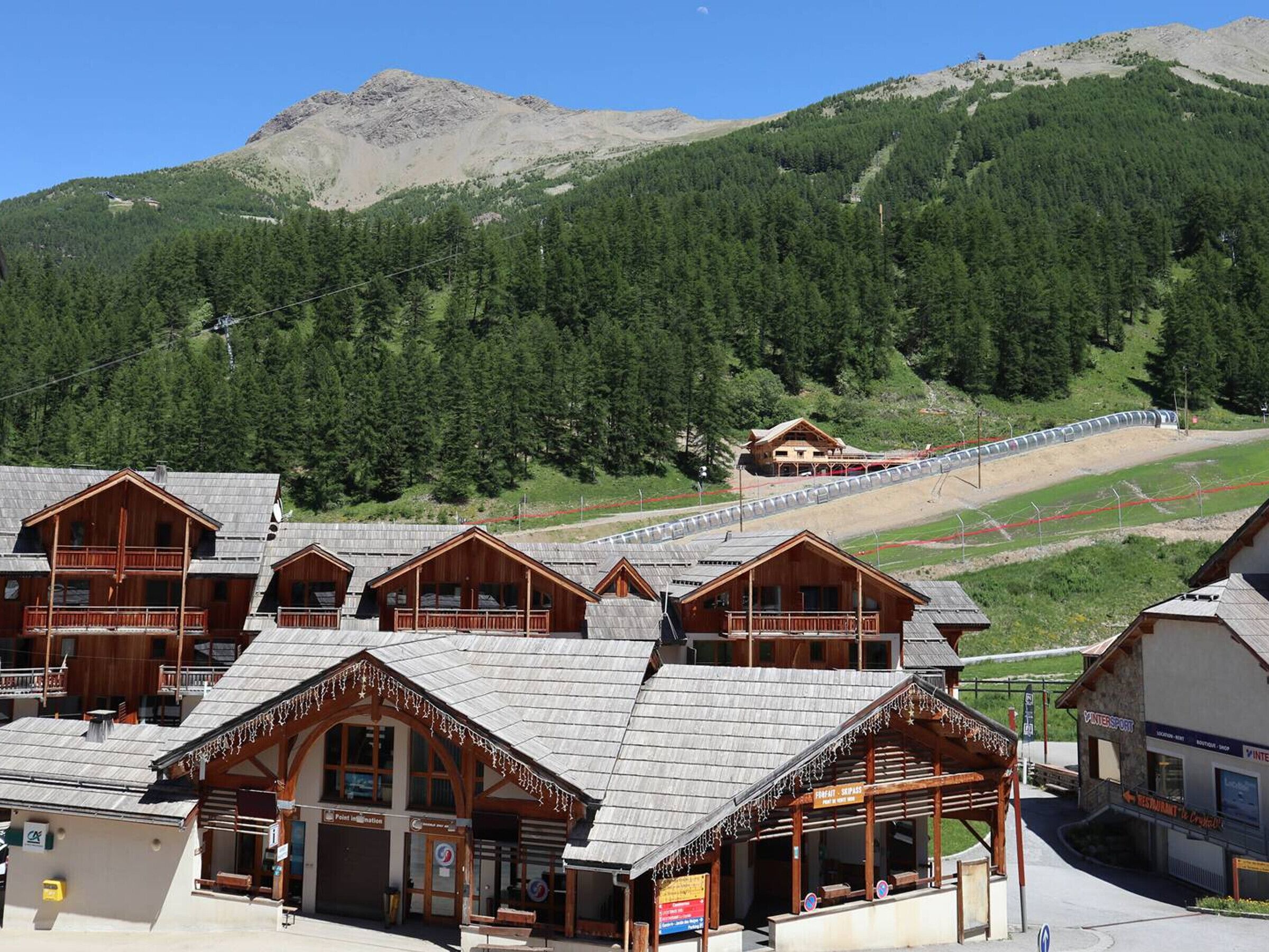 Un chalet de montagne comprenant plusieurs cabanes en bois, un télésiège et un restaurant.