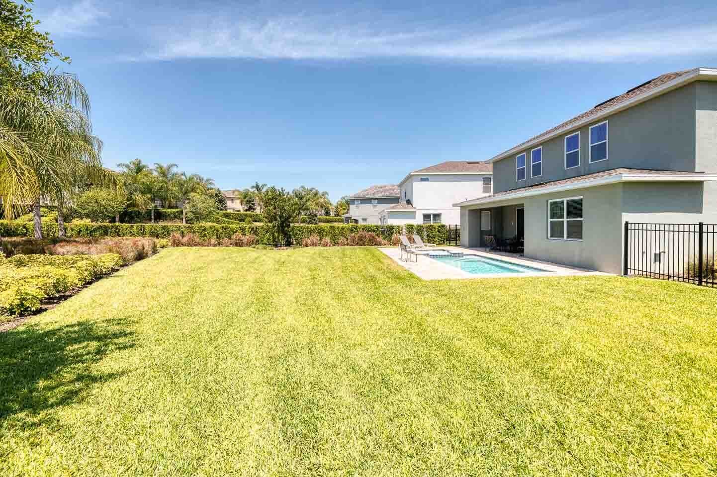 Il s’agit d’une propriété résidentielle dotée d’une pelouse bien entretenue, d’une piscine et d’une maison moderne avec un toit plat et de nombreuses fenêtres.