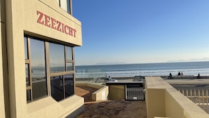 Ein Gebäude mit einem Schild mit der Aufschrift 'ZEIZEZICHT', das auf einen Strand mit Menschen und Autos blickt.