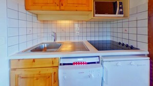 A compact kitchen with wooden cabinets, a sink, a microwave, and a Bosch dishwasher.