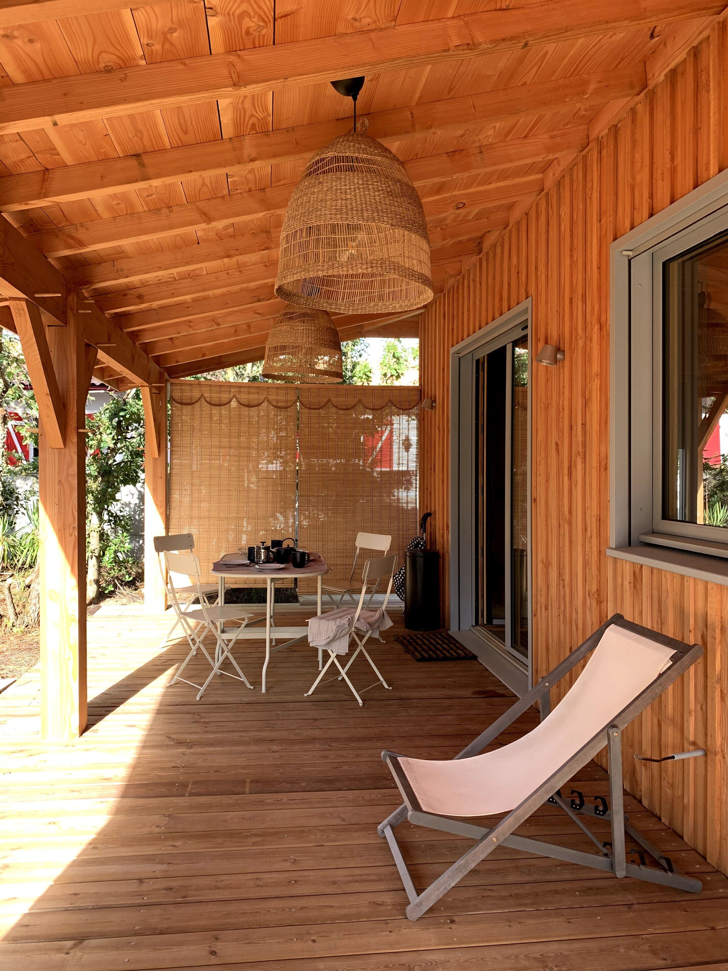 A wooden deck with a table and chairs, a hanging light fixture, and a sliding glass door.