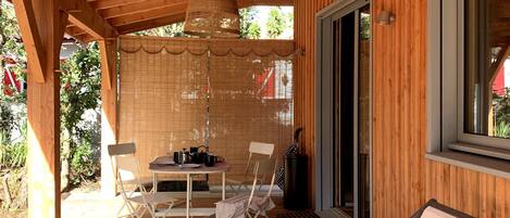 A wooden deck with a table and chairs, a hanging light fixture, and a sliding glass door.