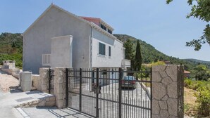 Una casa a due piani con facciata in pietra, un vialetto chiuso da un cancello e un'auto parcheggiata all'interno.