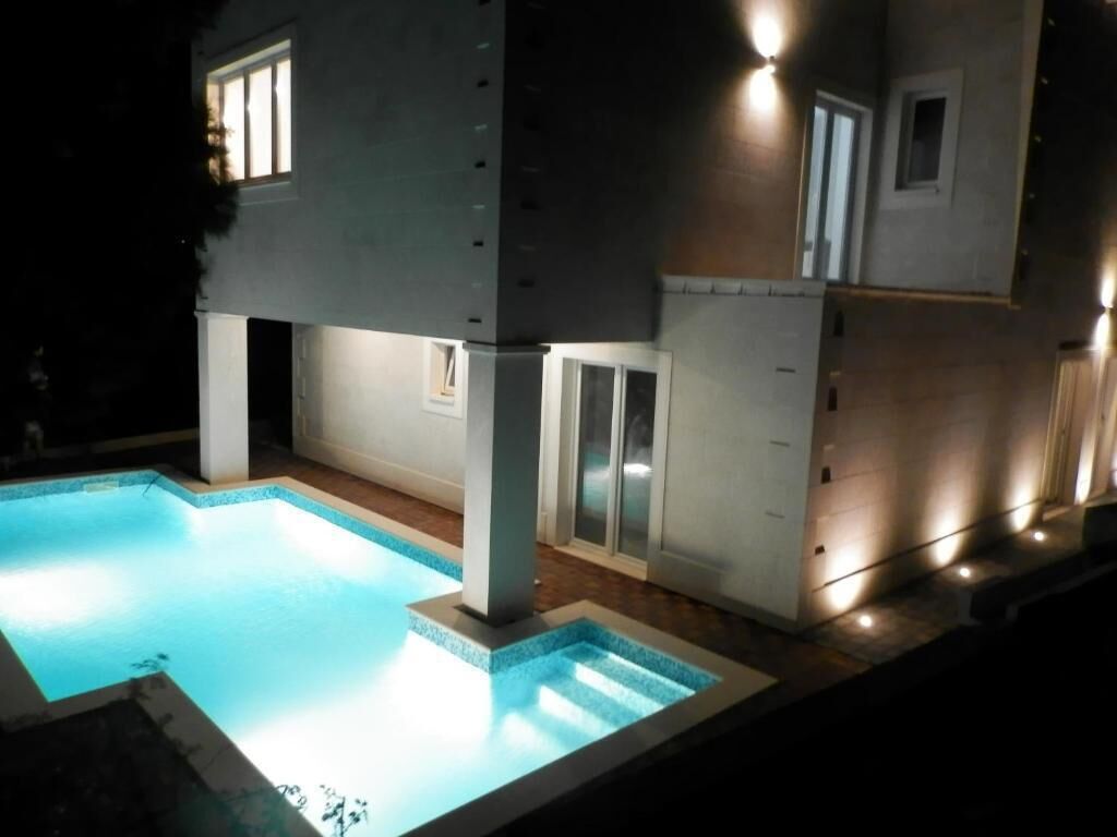 Un edificio moderno con piscina, iluminado por luces exteriores.