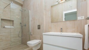Un bagno moderno con cabina doccia in vetro, un water e un mobile lavabo con specchio.