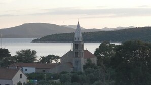 Una cittadina costiera con una chiesa imponente e un campanile slanciato, circondata da edifici residenziali e rigogliosa vegetazione.