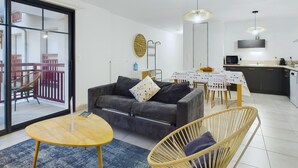 Un salon moderne comprenant un canapé, une table à manger et des chaises. Il y a également un coin cuisine avec un four à micro-ondes et un évier.
