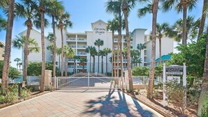A hotel entrance with a gated driveway, palm trees, and a sign indicating private property. - ☀Beachfront~Pool and Hot Tub~Beach SVC~3BR Crystal Dunes 304 (Destin)