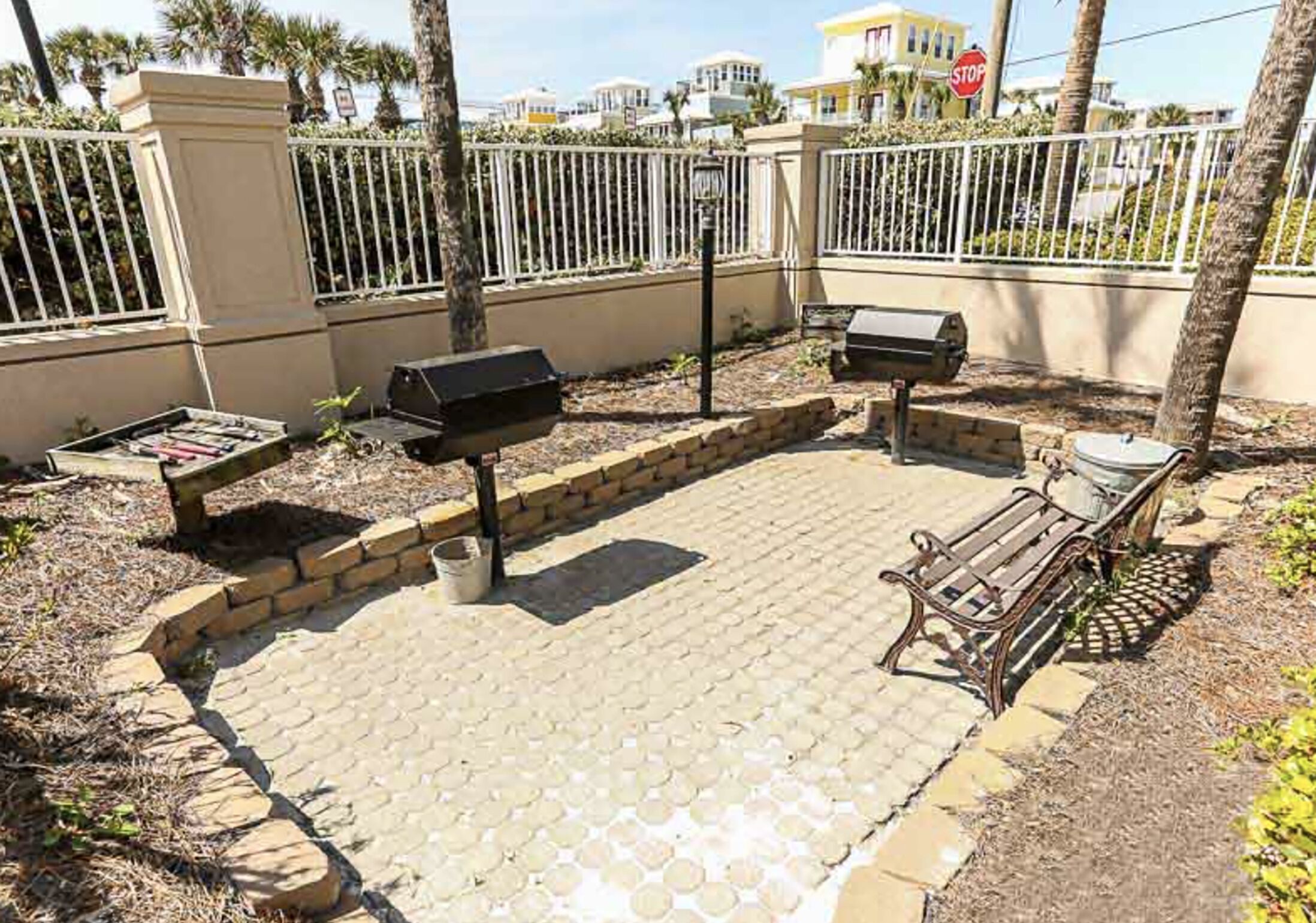 An outdoor patio area with a grill, a bench, and a paved walkway.
