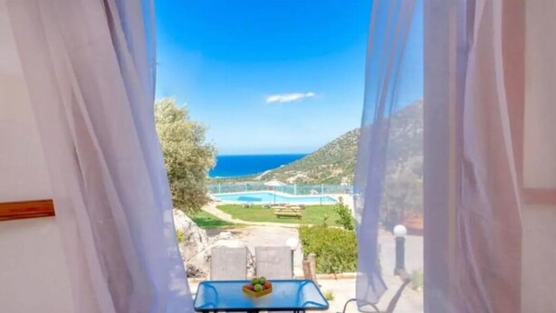 Un balcón con vistas a un paisaje costero, que incluye una piscina y zonas verdes.