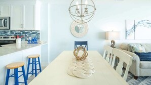 A modern kitchen with white cabinets, a stainless steel microwave, and a blue backsplash.