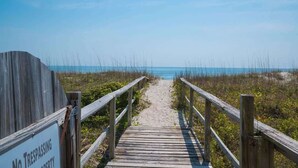 A wooden boardwalk leading to a beach with a 'No Trespassing' sign.