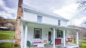 A white house with a stone chimney, a porch with green chairs, and a red mailbox. - Fulkerson-Hilton historic homestead (Hiltons)