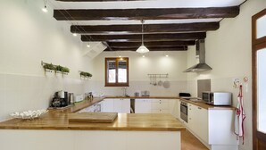 A kitchen with wooden countertops, white cabinets, a central island, hanging plants, and a window. - La Maison de Campagne - Le Farat (Auvillar)