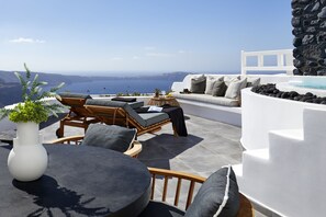 Une terrasse avec des sièges d’extérieur, un canapé blanc et un mur en pierre.