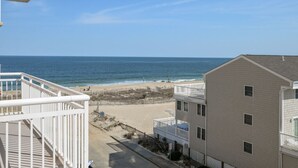 A beachfront property with a balcony overlooking the ocean, a sandy beach, and adjacent buildings. - Luxury 3 bedroom, 3 bath on the ocean with indoor and outdoor pools (Ocean City)
