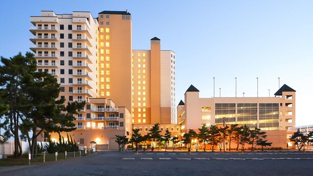 A multi-story hotel with balconies, a parking lot, and a building with large windows. - Luxury 3 bedroom, 3 bath on the ocean with indoor and outdoor pools (Ocean City)