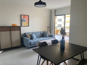 A modern living room with a sofa, a dining table, and a kitchen area. - Tamaris playa 4ºC Solo Familias! (Playa Xeraco)
