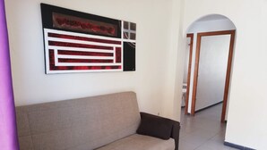 Un saló amb un sofà, una taula de centre de fusta i una obra d'art abstracta penjada a la paret.