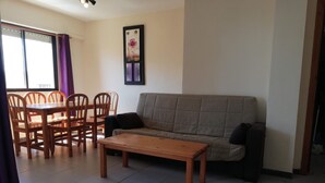 Ein Wohnzimmer mit einer Couch, einem Holztisch und einem Essbereich mit Stühlen und einem Tisch.