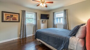A bedroom with a bed, a ceiling fan, a TV, and a dresser. - Cozy Connected Duplex Home with Driveway (Atlanta)
