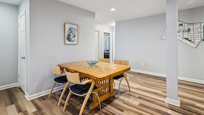 A dining area with a wooden table and chairs, a framed artwork on the wall, and a map on the adjacent wall.