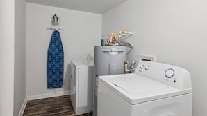 A laundry room with a front-loading washer and dryer, a water heater, and a drying rack.