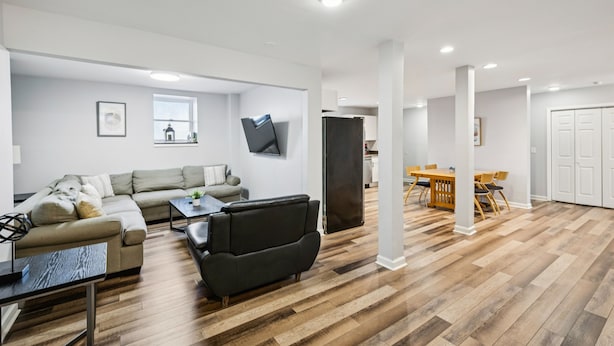 A modern living room with a sofa, a black armchair, a coffee table, and a dining area with a table and chairs.