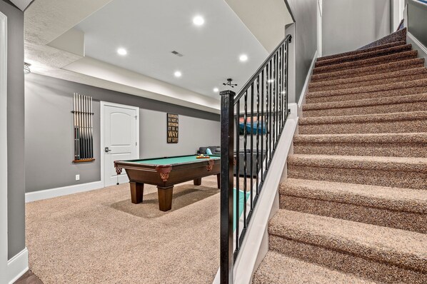 A home interior with a pool table, a staircase, and a door. - 4 King beds! Private, Heated Pool! Theater Room! Game Room! Bunks!! (Sevierville)