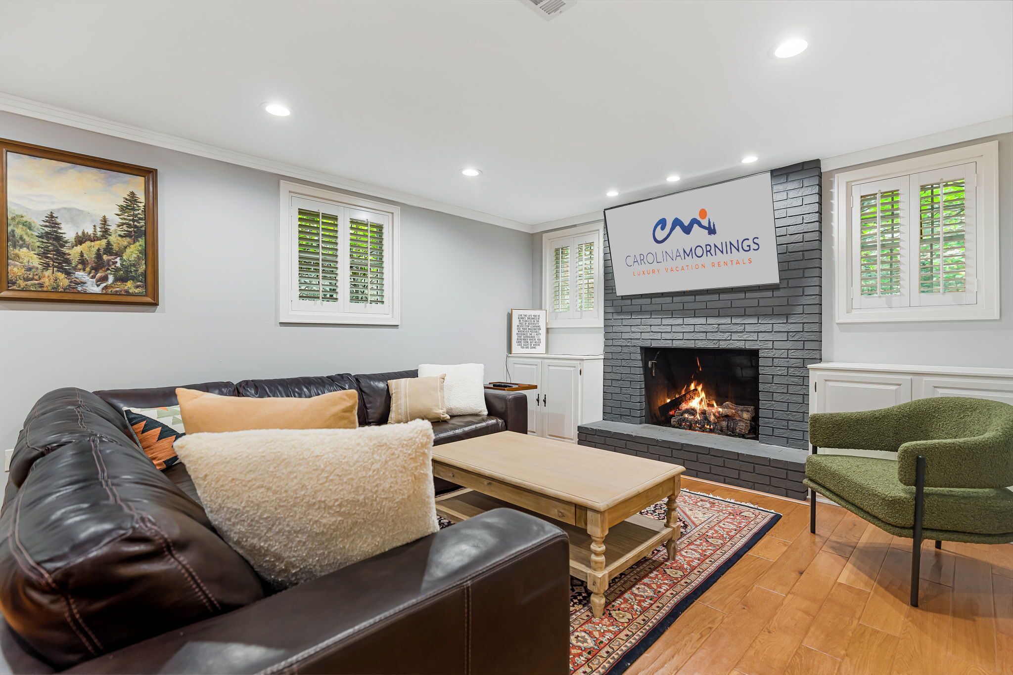 A modern living room with a fireplace, a sofa, a coffee table, and a green armchair.
