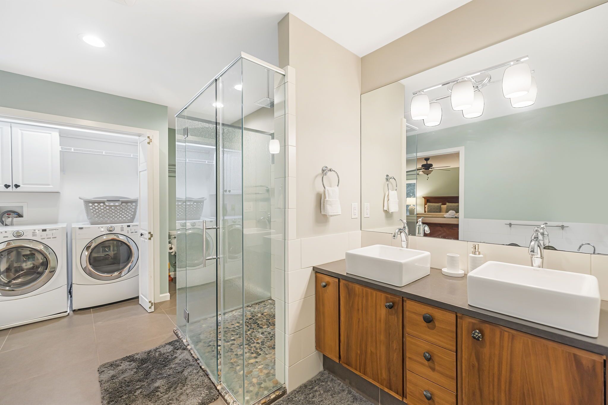 A modern bathroom with a glass-enclosed shower, dual sinks, and a large mirror.