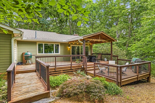 A house with a deck, outdoor seating, and a grill area.