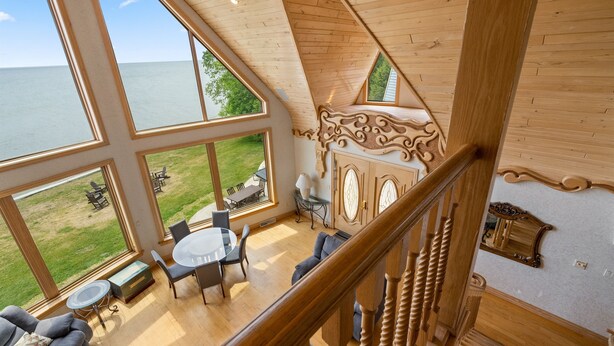 Ein geräumiges Zimmer mit großen Fenstern, die auf eine Wiese und ein Gewässer blicken.